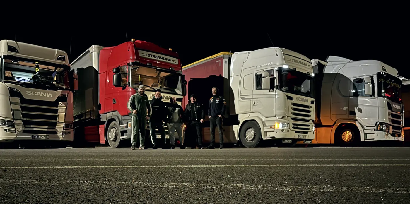 Kierowcy LOBOTRANSPORT przy ciężarówkach nocą