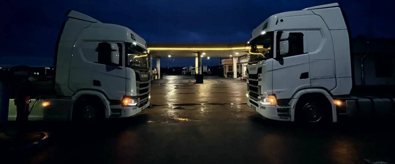 Dwa ciągniki Scania nocą na oświetlonym placu